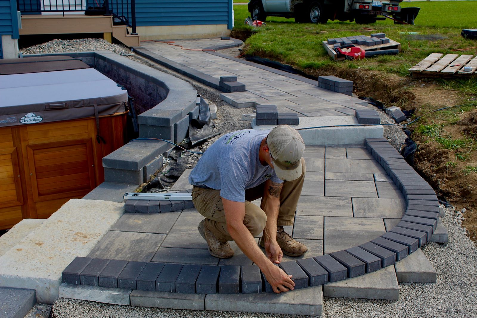 ARP crew member setting curved pavers around a built-in hot tub patio
