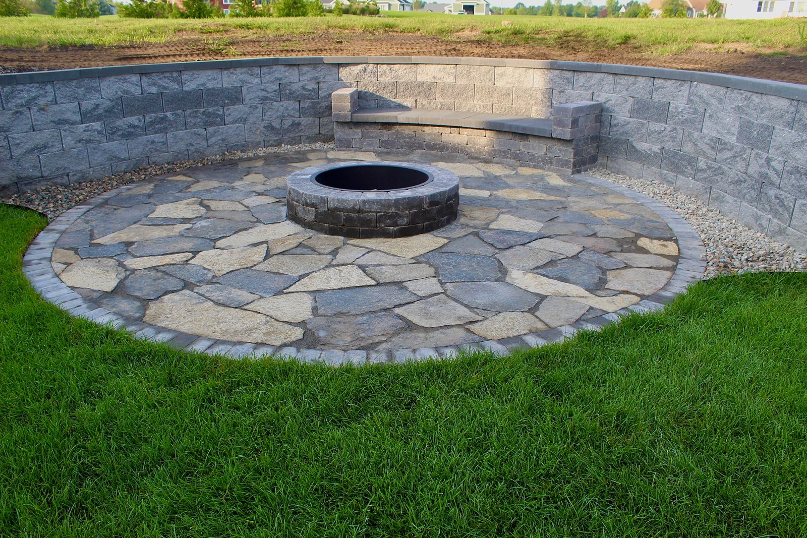 Circular flagstone fire pit patio with a built-in retaining wall bench