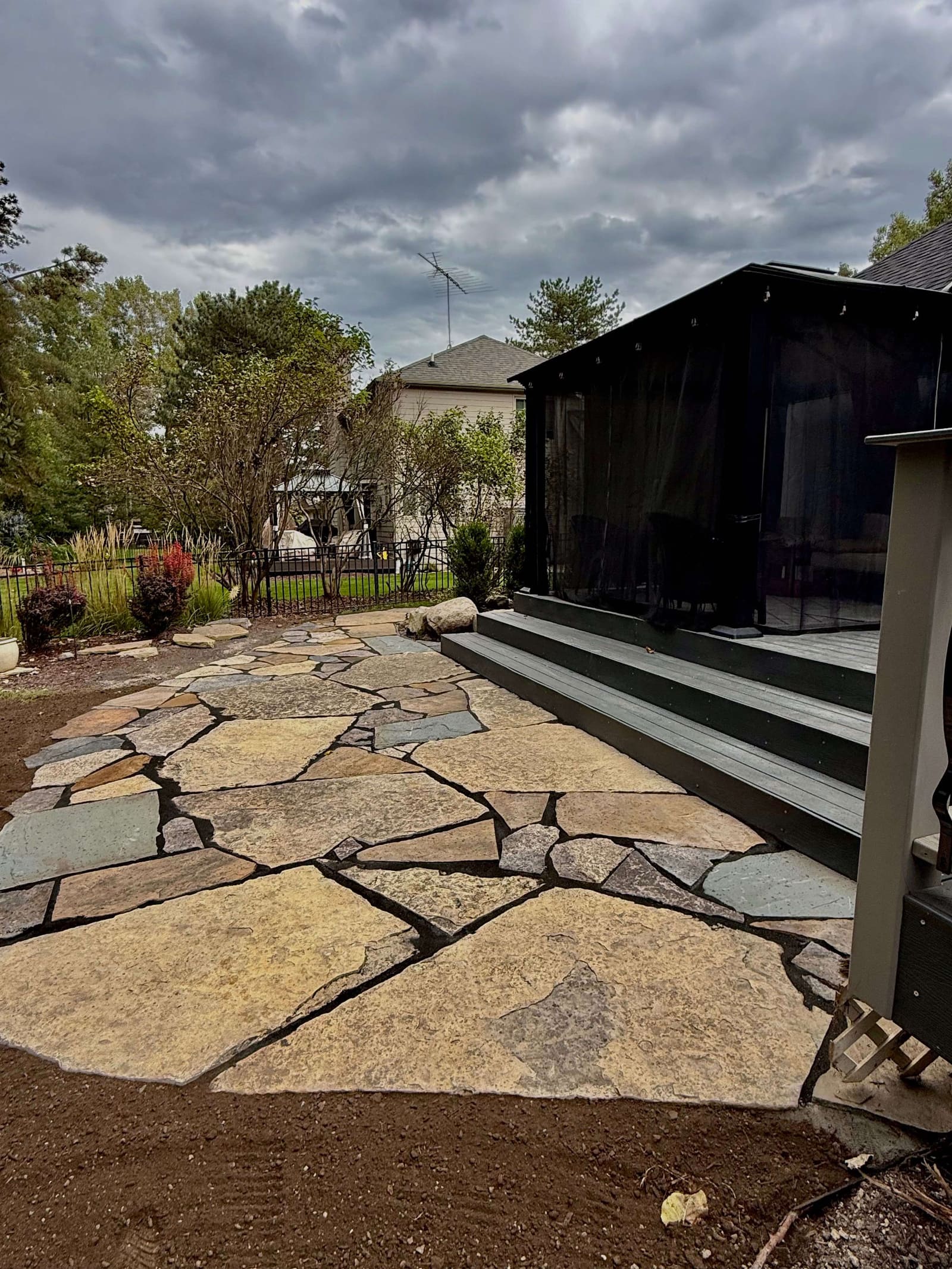 Flagstone patio leading up to a custom screened porch addition