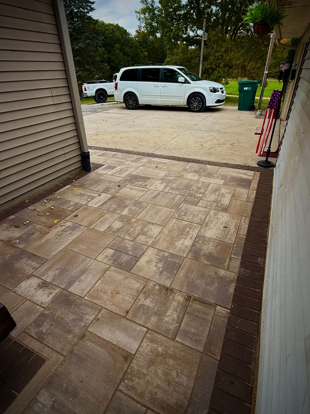 Paver landing pad with dark border tied into an existing concrete driveway